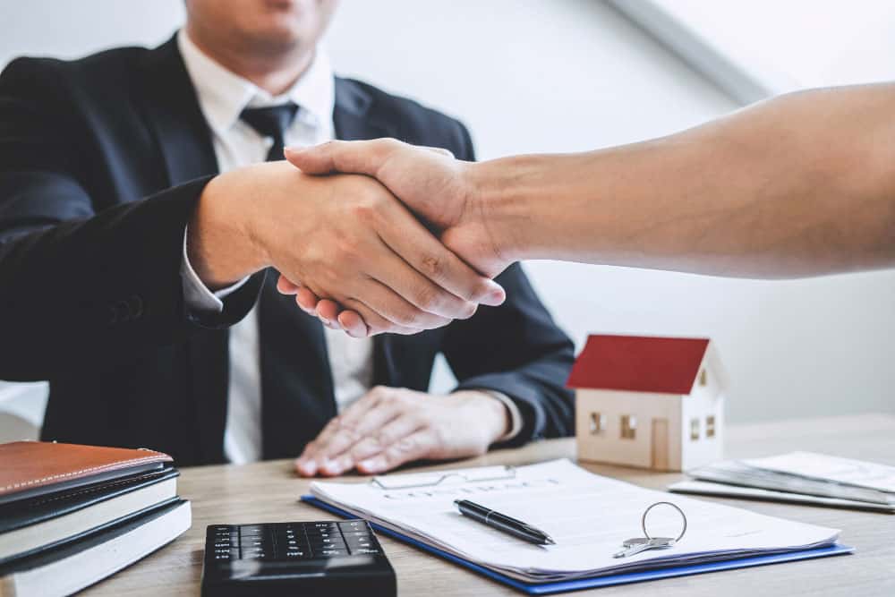 finishing successful deal real estate broker client shaking hands after signing contract approved application form concerning mortgage loan offer house insurance