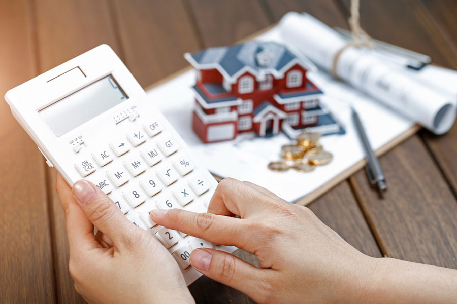 female-hand-operating-calculator-in-front-of-villa-house-model-2